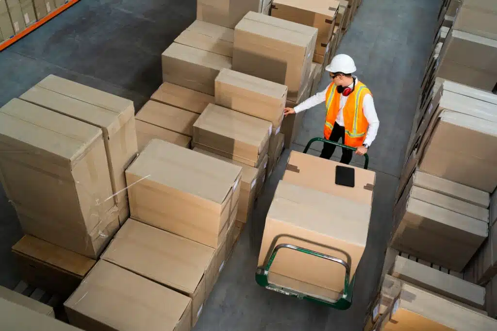Logistic warehouse worker delivering boxes on a trolley